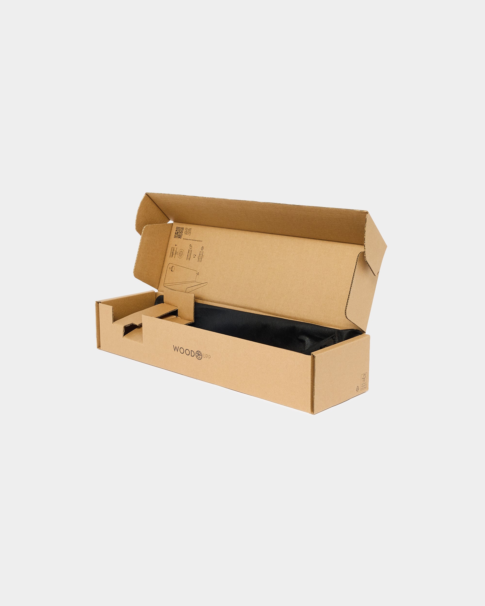 Open cardboard box with compartments, partially filled with eco-friendly black packaging material, on a plain white background; suitable for acoustic panel shipment.
